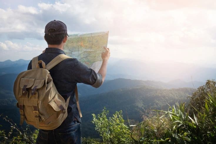 A traveller checking a map on a hillside